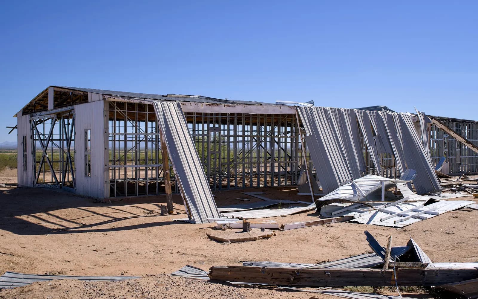 Wind-damaged commercial metal building with torn roof and wall panels
