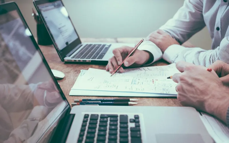 Hands reviewing claim documents next to a laptop