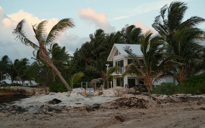 Beach house with palm trees and storm debris after high winds
