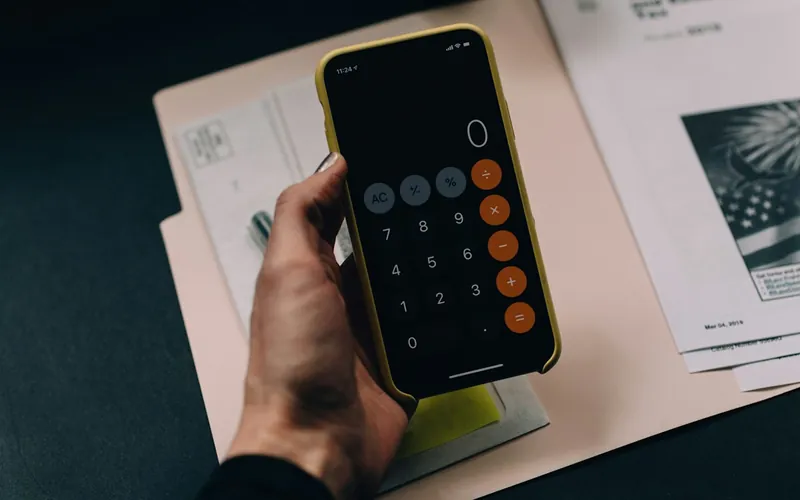 Calculator on a phone over printed estimate pages