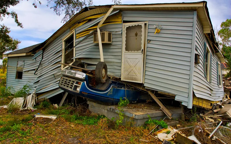 Storm-damaged house with debris in the yard