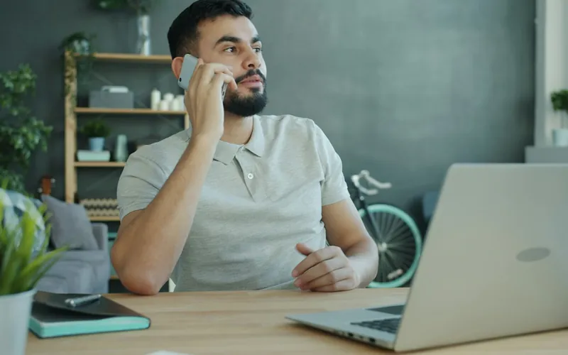 Homeowner on a phone call at a desk with a laptop