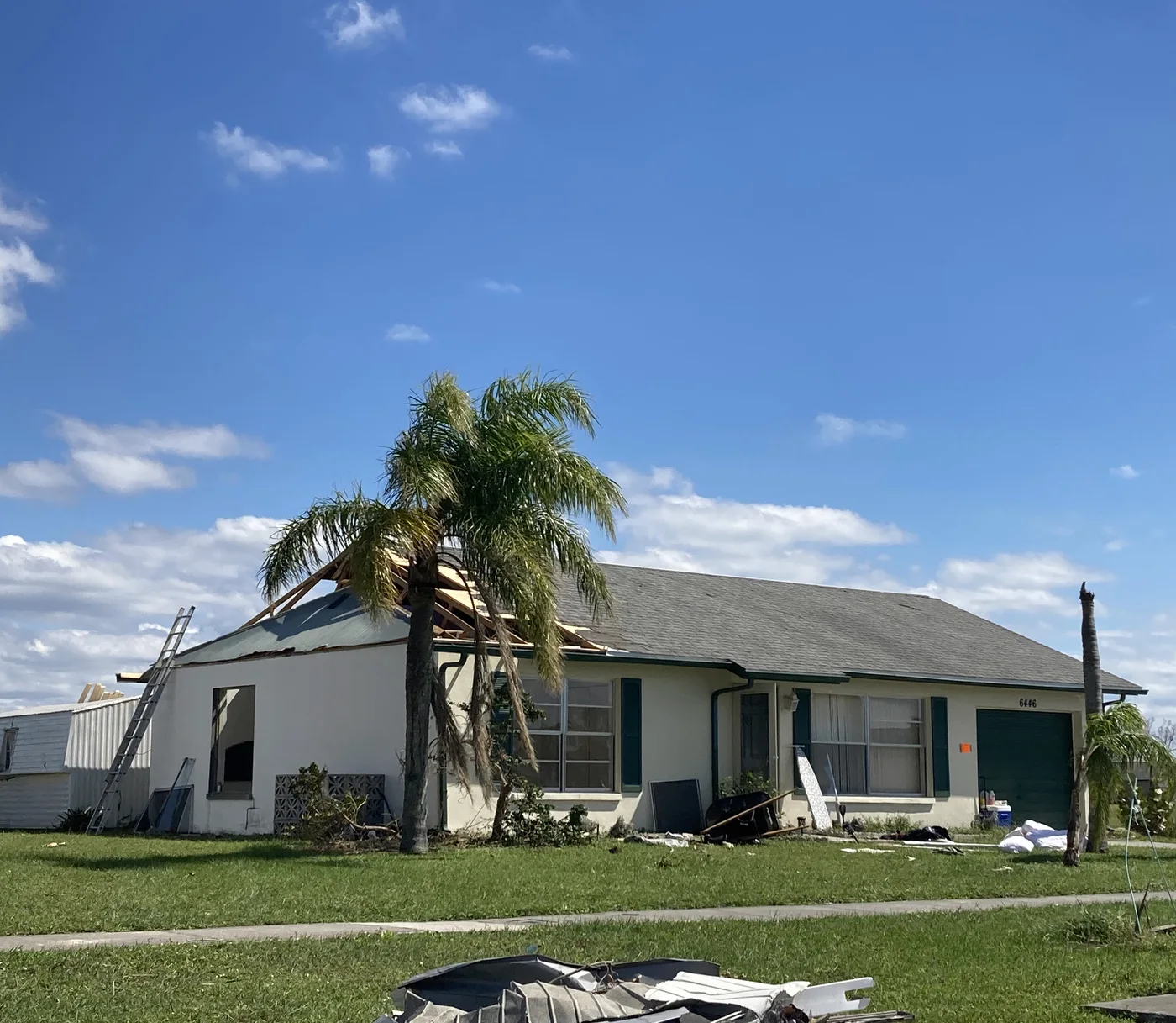 Illustrative Florida home with torn roof and palm trees after Hurricane Ian — not a client file