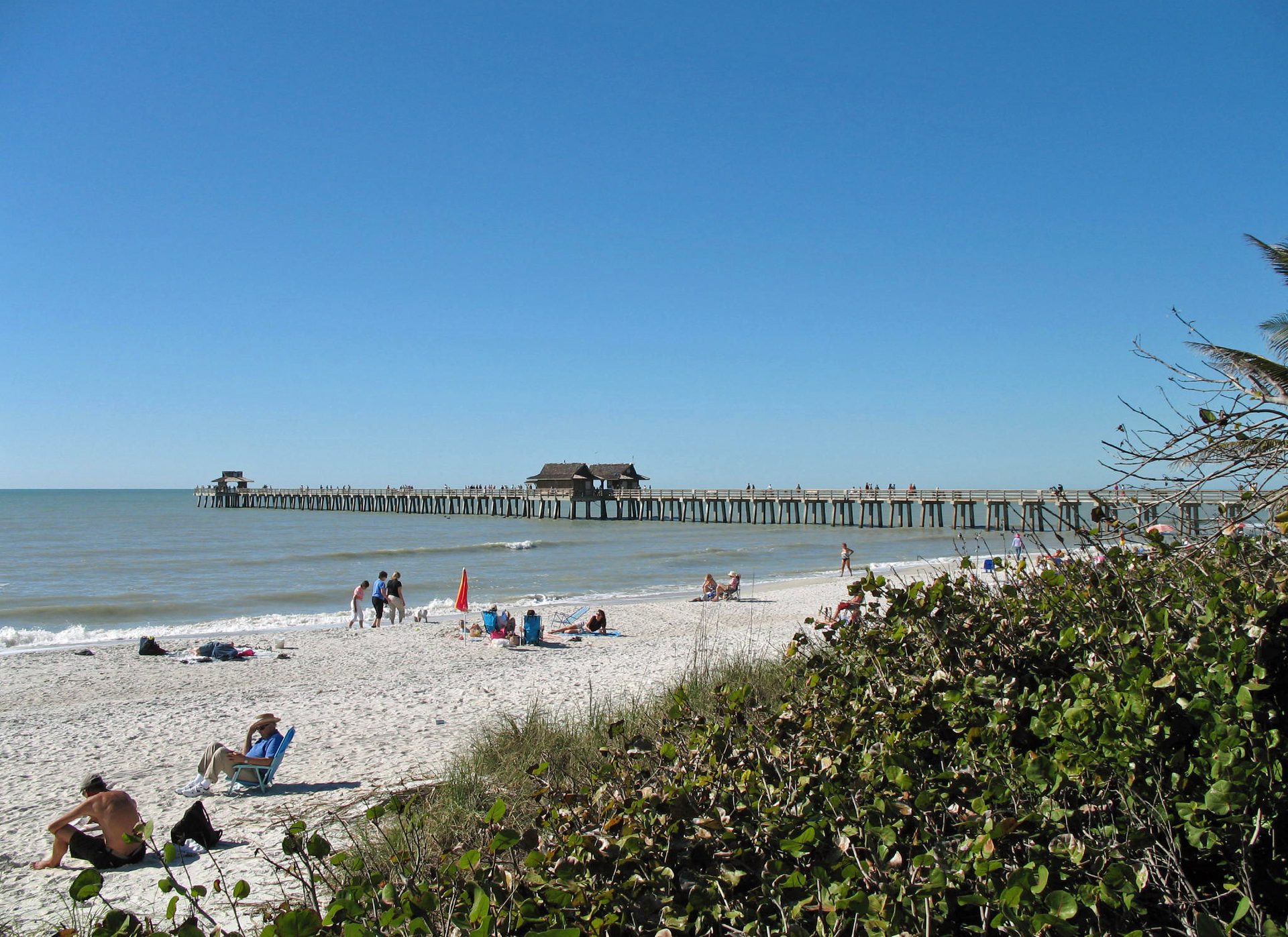 Naples Pier stretching into the Gulf of Mexico from a sunny Naples beach, Collier County