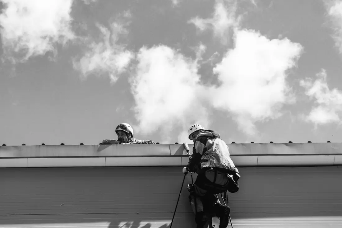 Two workers in safety gear inspecting a rooftop
